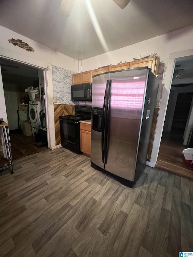 kitchen featuring black appliances, dark wood-style flooring, a ceiling fan, washer / clothes dryer, and brown cabinets