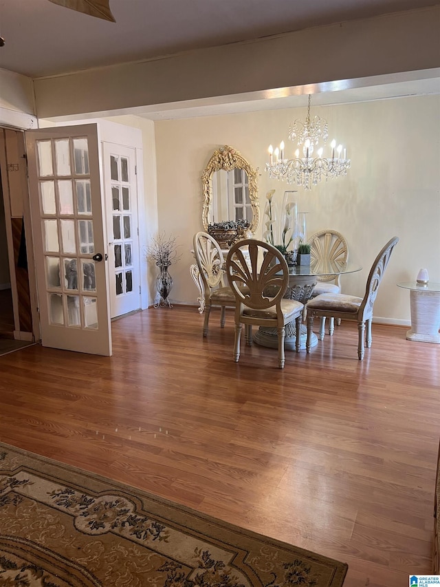 dining area with wood finished floors, a chandelier, and french doors