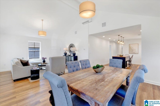 dining space with high vaulted ceiling and light wood-type flooring