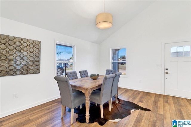 dining room with high vaulted ceiling and wood-type flooring