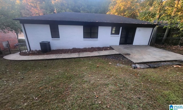 rear view of property featuring a lawn and central AC unit