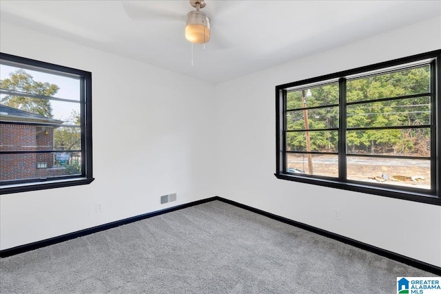 carpeted spare room featuring plenty of natural light and ceiling fan