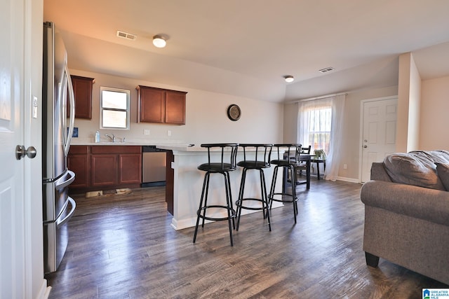 kitchen featuring a breakfast bar area, stainless steel appliances, sink, a center island, and dark hardwood / wood-style flooring