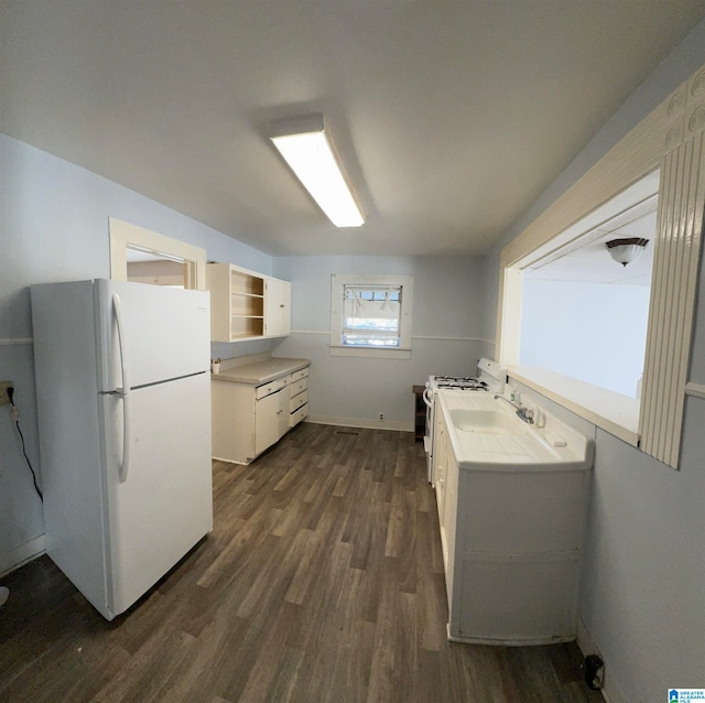 kitchen featuring white appliances, dark wood-type flooring, sink, and white cabinets