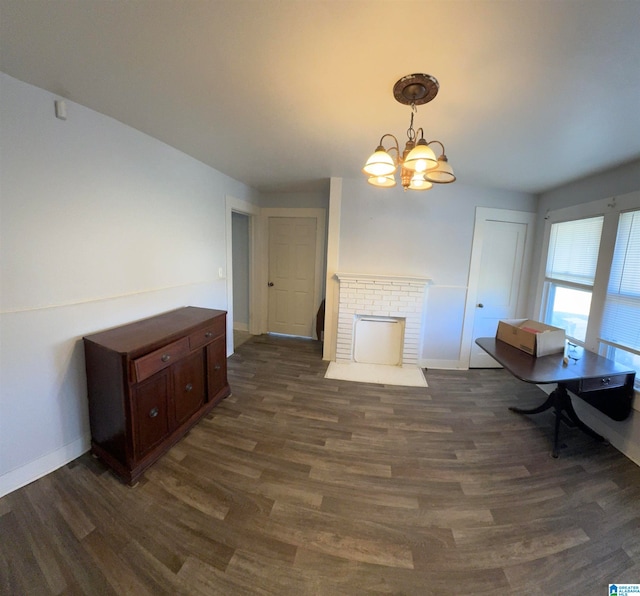 dining space with dark hardwood / wood-style flooring, a chandelier, and a brick fireplace