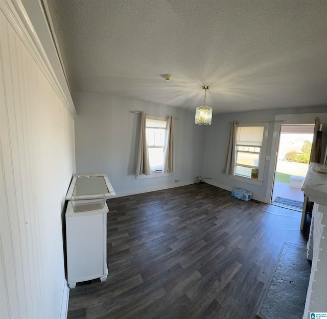 unfurnished living room featuring a textured ceiling, a healthy amount of sunlight, and dark hardwood / wood-style flooring