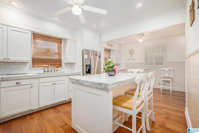 kitchen with white cabinets, sink, light wood-type flooring, and stainless steel fridge with ice dispenser