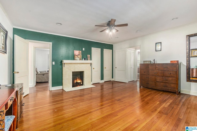 living room with ornamental molding, a fireplace, hardwood / wood-style flooring, and ceiling fan