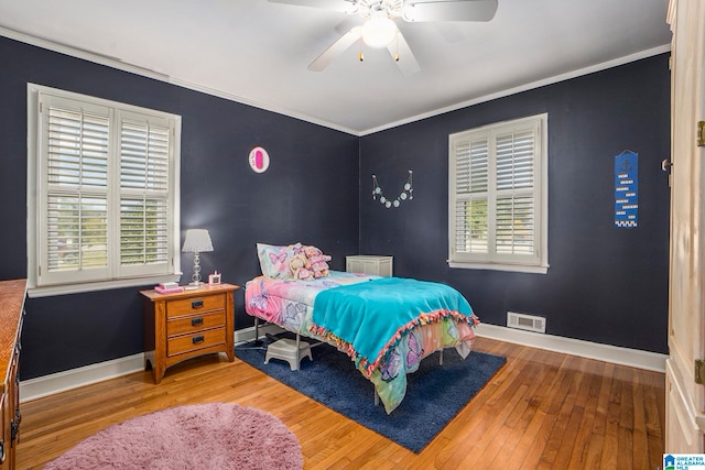 bedroom with multiple windows, hardwood / wood-style floors, crown molding, and ceiling fan