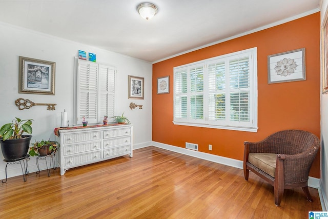 living area with light hardwood / wood-style flooring and ornamental molding