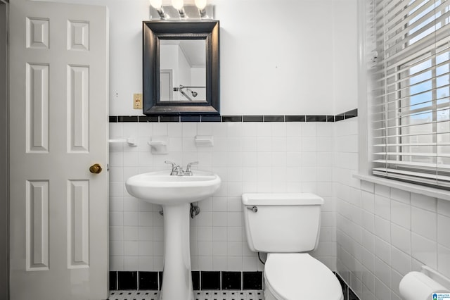 bathroom with tile walls, sink, and toilet