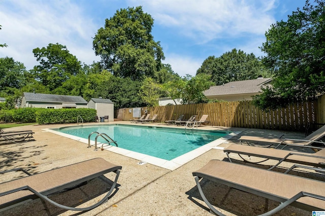 view of swimming pool featuring a shed and a patio area