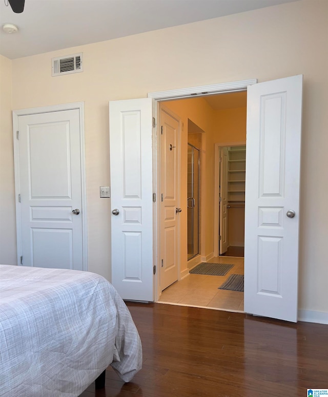 bedroom with a spacious closet and dark hardwood / wood-style floors