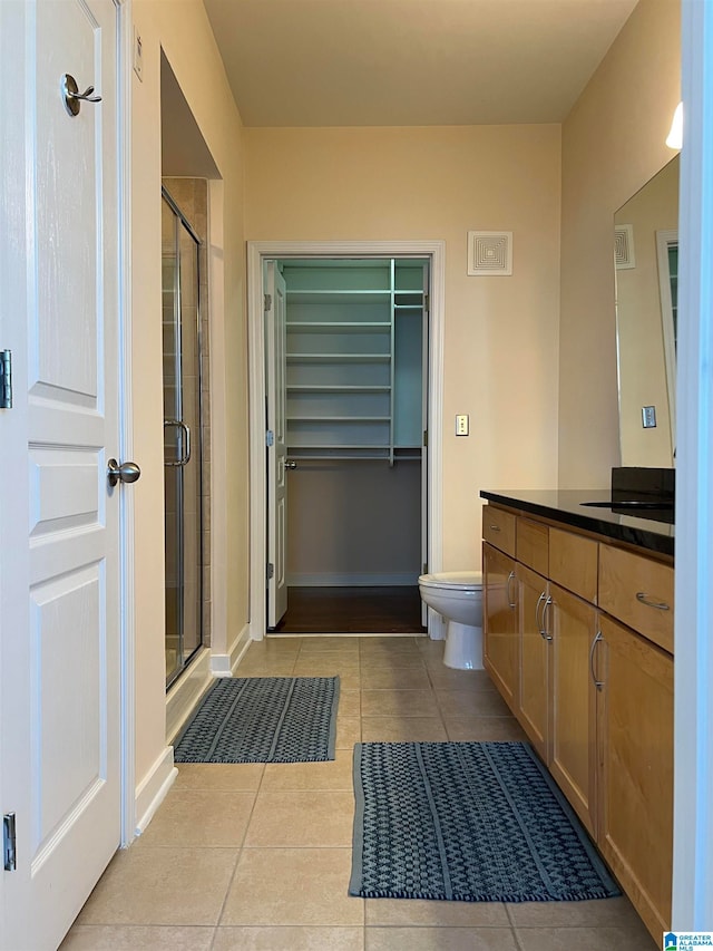 bathroom with vanity, toilet, tile patterned floors, and a shower with door