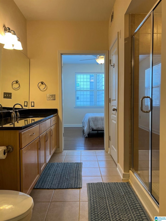 bathroom featuring vanity, a shower with shower door, toilet, and tile patterned floors