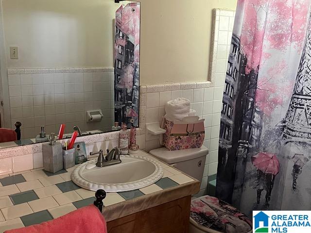 bathroom featuring tile walls, vanity, and toilet