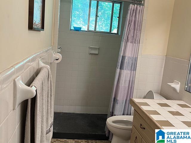 bathroom with vanity, toilet, tile walls, and a shower with curtain