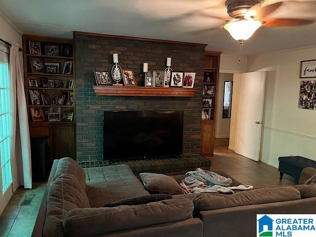 tiled living room with crown molding, a fireplace, and ceiling fan