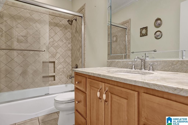 full bathroom with tile patterned flooring, combined bath / shower with glass door, toilet, vanity, and ornamental molding