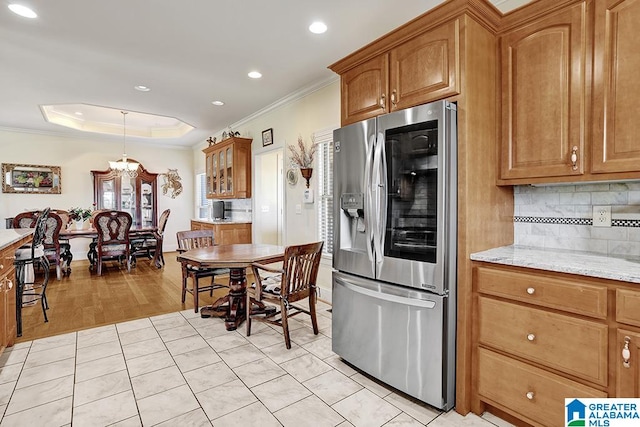 kitchen with stainless steel refrigerator with ice dispenser, ornamental molding, tasteful backsplash, light hardwood / wood-style floors, and light stone counters