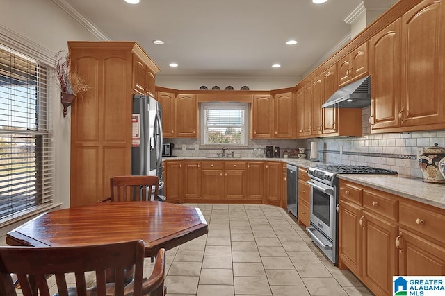 kitchen featuring light stone countertops, sink, stainless steel appliances, crown molding, and decorative backsplash