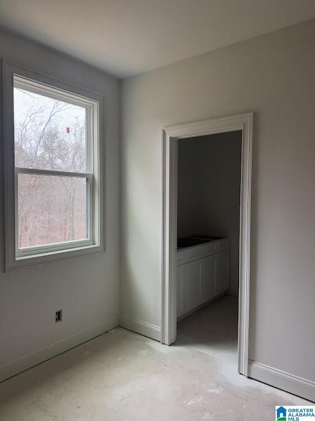 unfurnished bedroom with unfinished concrete floors and baseboards