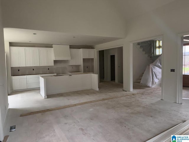 kitchen with wall chimney exhaust hood, a kitchen island, and white cabinetry