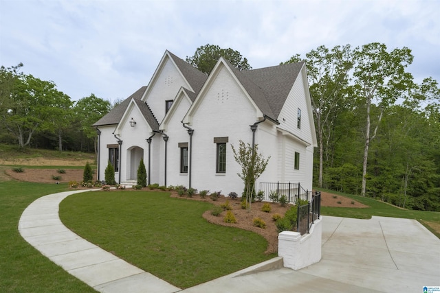 french country home with brick siding, roof with shingles, and a front yard