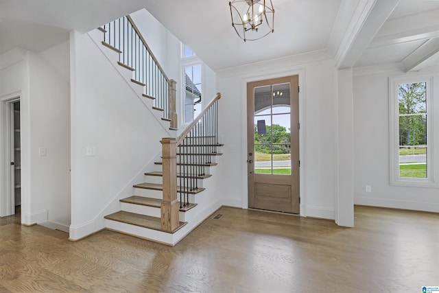 foyer entrance with plenty of natural light, stairs, wood finished floors, and a notable chandelier