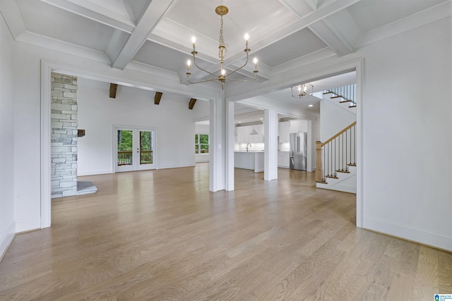 unfurnished living room with a notable chandelier, light wood-style flooring, beamed ceiling, stairway, and coffered ceiling