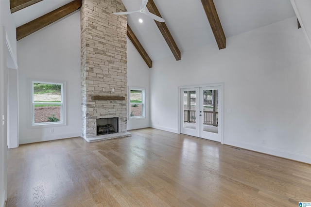 unfurnished living room featuring high vaulted ceiling, ceiling fan, beamed ceiling, and wood finished floors