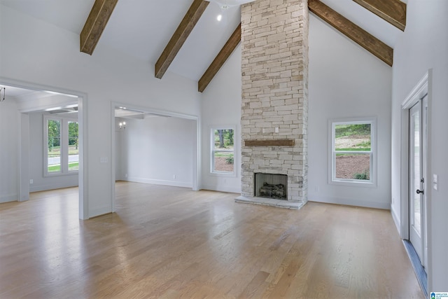 unfurnished living room featuring a healthy amount of sunlight, high vaulted ceiling, baseboards, and beam ceiling