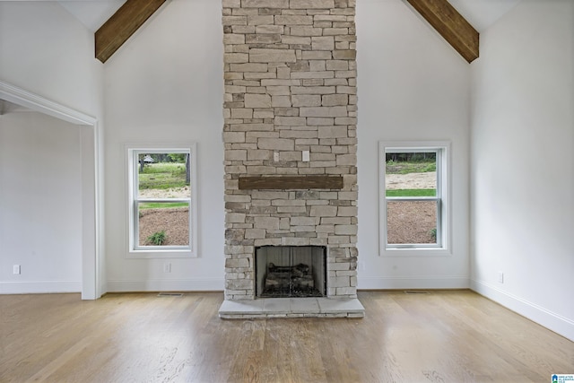 unfurnished living room with high vaulted ceiling, beam ceiling, and wood finished floors