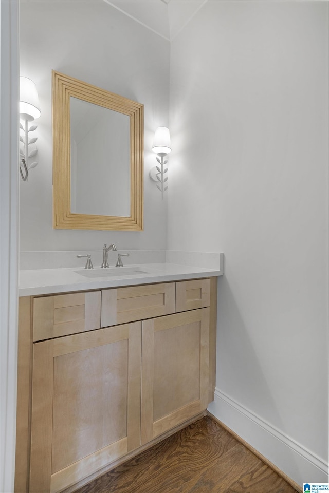 bathroom featuring baseboards, wood finished floors, and vanity