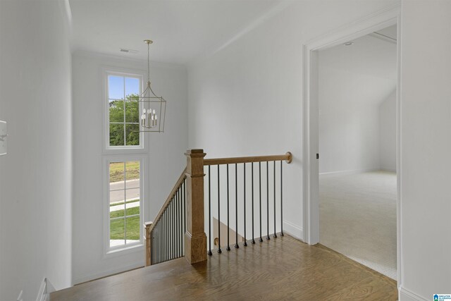 corridor featuring visible vents, plenty of natural light, a chandelier, and an upstairs landing