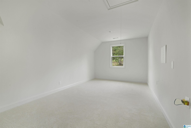 additional living space with baseboards, light carpet, attic access, and lofted ceiling