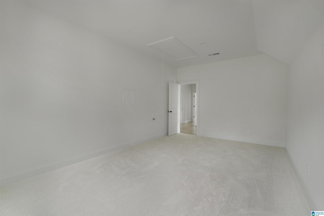 empty room featuring visible vents, light carpet, attic access, and lofted ceiling