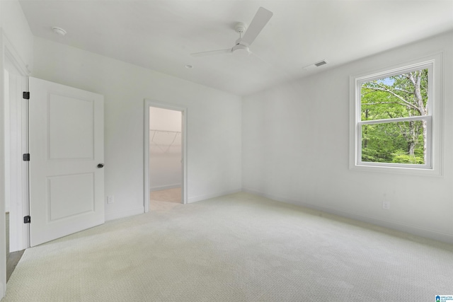 unfurnished bedroom with baseboards, visible vents, light carpet, and a walk in closet