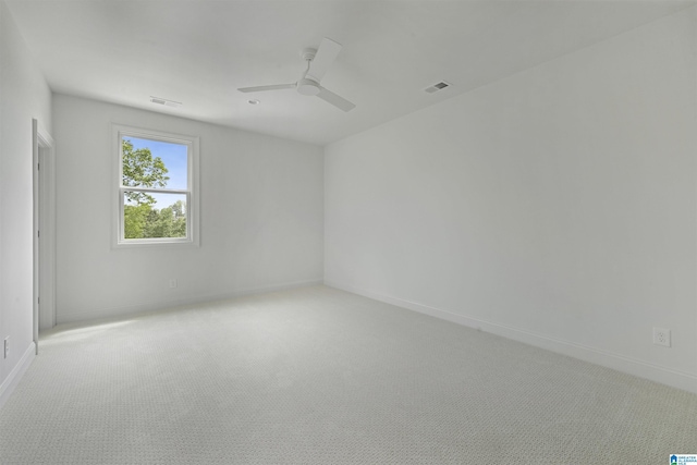 carpeted spare room featuring visible vents, baseboards, and ceiling fan