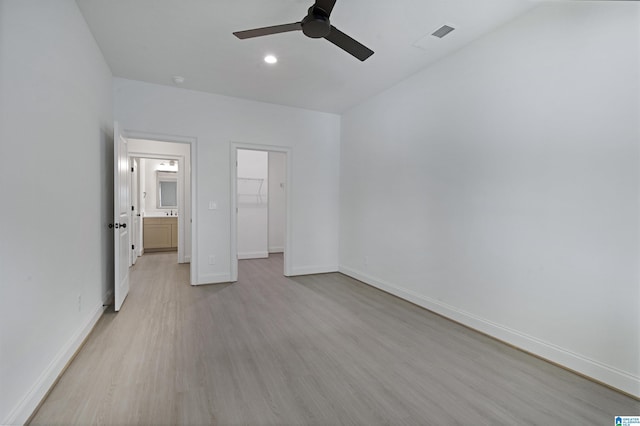 unfurnished bedroom with a walk in closet, a ceiling fan, light wood-type flooring, baseboards, and a closet