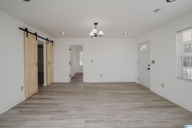 spare room with light hardwood / wood-style floors and a barn door