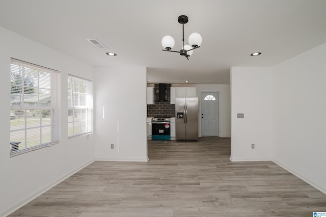 unfurnished living room featuring light hardwood / wood-style flooring and an inviting chandelier