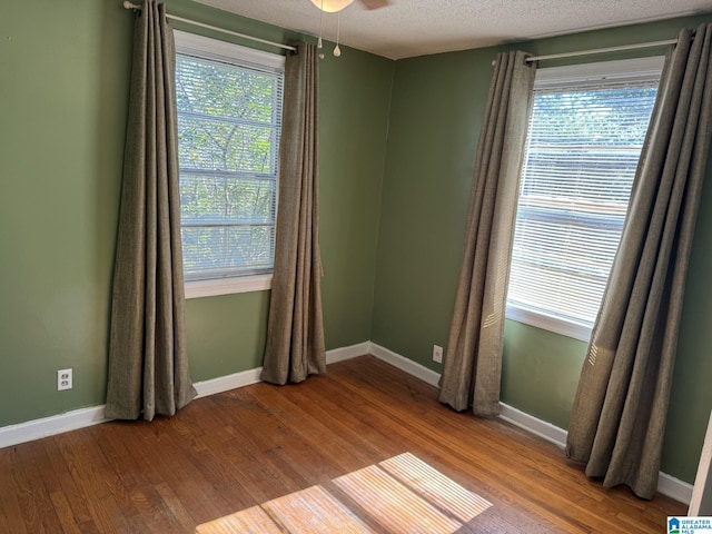 spare room with a textured ceiling, wood-type flooring, plenty of natural light, and ceiling fan