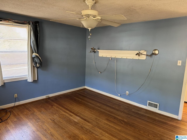 spare room featuring dark wood-type flooring, ceiling fan, and a textured ceiling