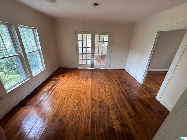 spare room featuring dark hardwood / wood-style flooring, ornamental molding, french doors, and plenty of natural light