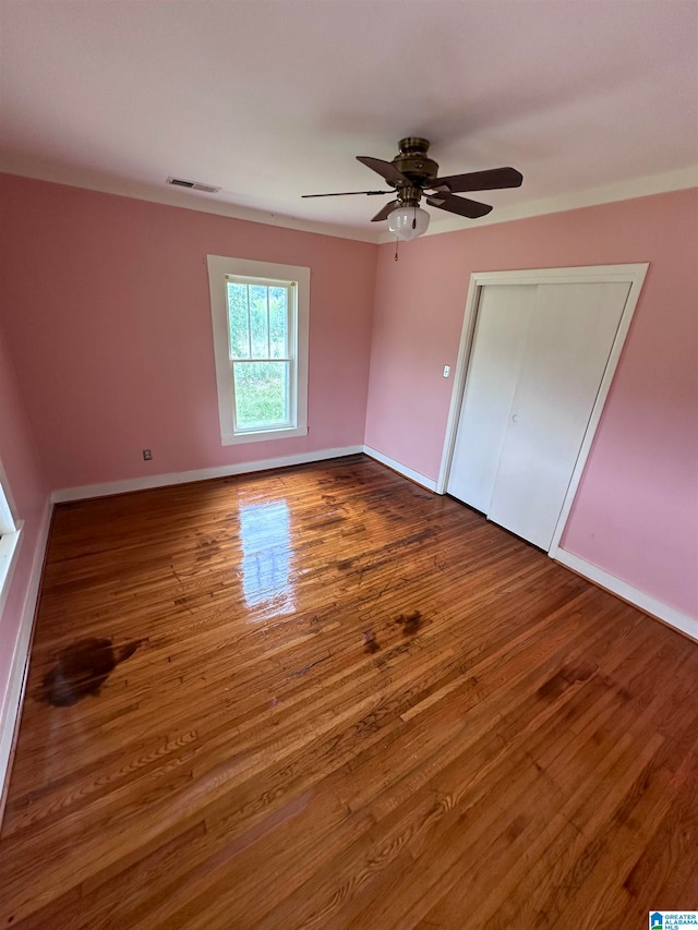 unfurnished bedroom with a closet, hardwood / wood-style flooring, and ceiling fan