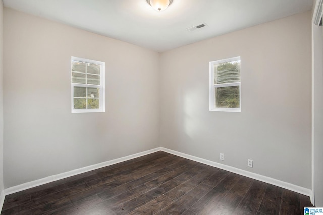 empty room with dark hardwood / wood-style floors and plenty of natural light