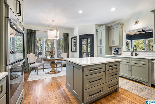 kitchen featuring sink, a healthy amount of sunlight, wood-type flooring, and decorative light fixtures