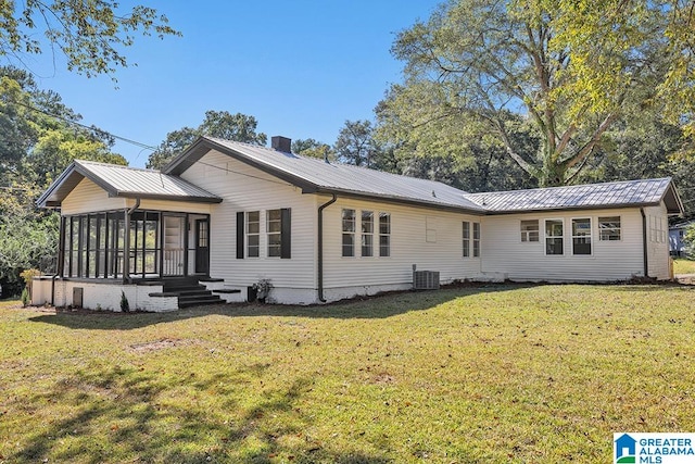 rear view of house with a yard, a sunroom, and central AC unit