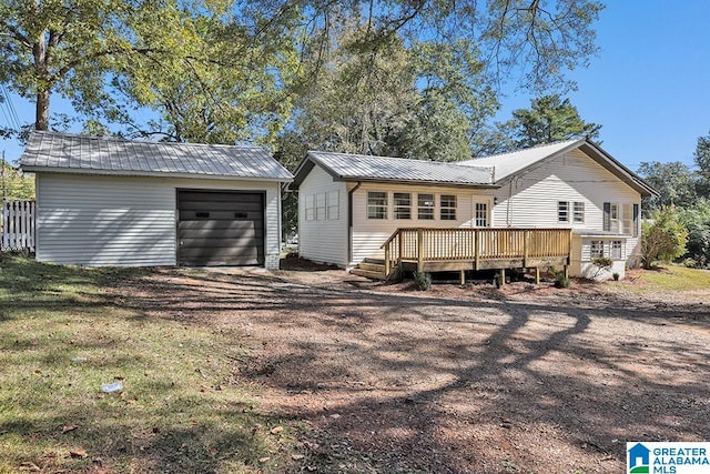 rear view of property featuring a wooden deck, a garage, a lawn, and an outdoor structure